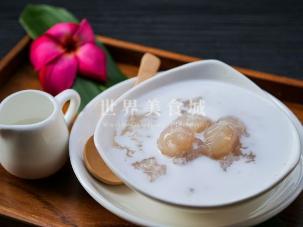 Longan sticky rice served on a wooden tray with tropical flowers next to it