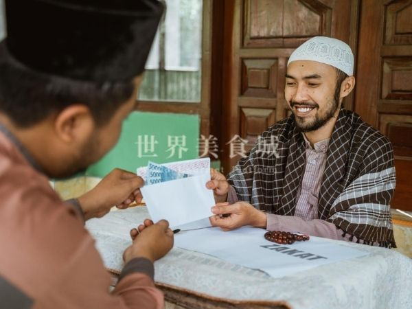 身穿传统服饰的穆斯林把放着印尼盾钞票的信封袋捐献出去